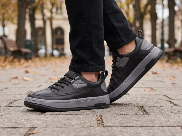 chunky sole leather casual sneakers in black, worn on foot on a city park path, soft daylight lifestyle photo