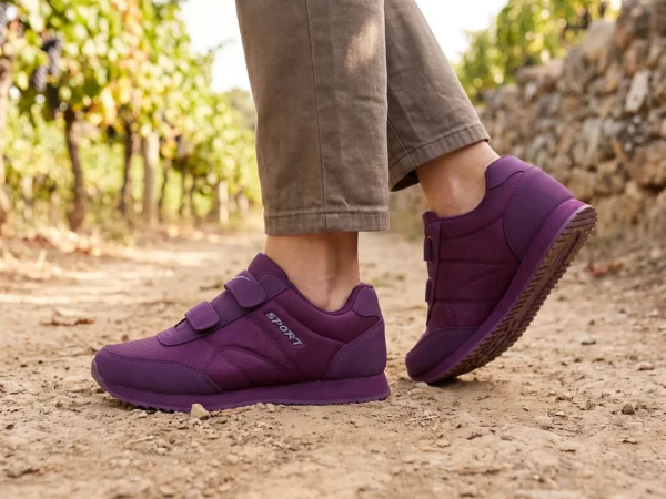 cushioned walking sneakers hook-and-loop slip-on non-slip comfort shoes in purple, worn on foot on a vineyard path, soft daylight lifestyle photo