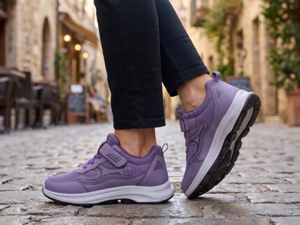 hook-and-loop walking sneakers slip-on soft sole non-slip comfort shoes for everyday walking in purple, worn on foot on a cobblestone old-town lane, soft daylight lifestyle photo