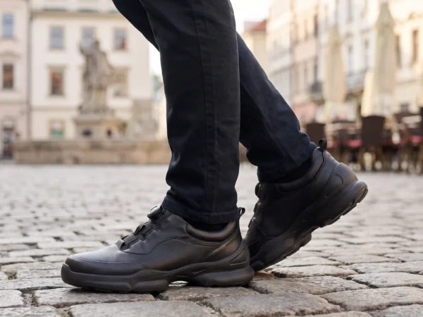 lightweight boa walking sneakers in black, worn on foot on a old-town square, soft daylight lifestyle photo