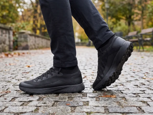 lightweight trail running sneakers in black, worn on foot on a city park path, soft daylight lifestyle photo