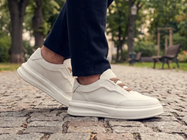 genuine leather platform sneakers in white, worn on foot on a city park path, soft daylight lifestyle photo