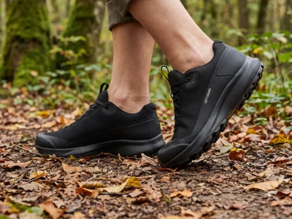unisex lightweight hiking shoes - breathable outdoor walking  trail shoes couple style in black, worn on foot on a forest trail, soft daylight lifestyle photo