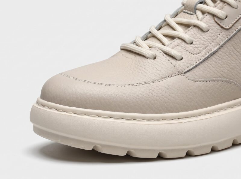 Toe close-up of beige menu2019s leather casual sneaker showing stitching