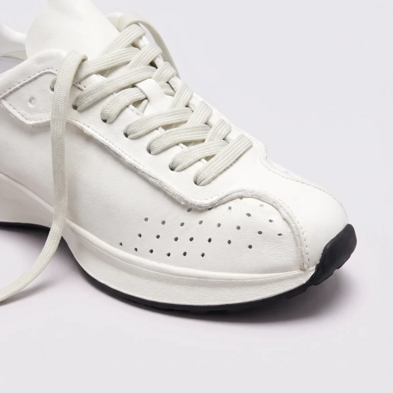 cream leather chunky lace-up dad sneakers in cream, close-up view of the toe on a light gray background