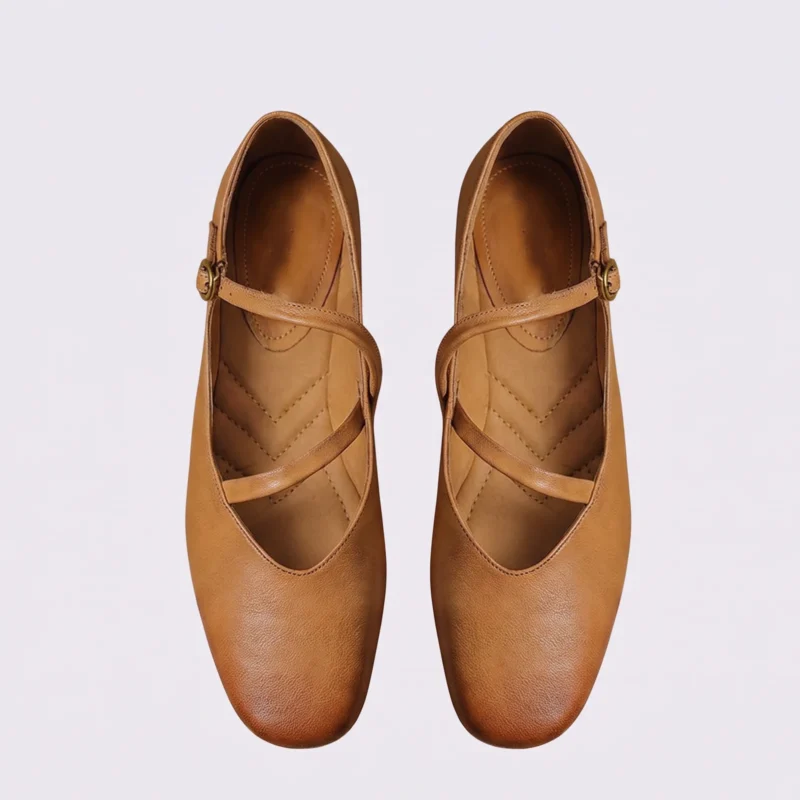 Top-down view of a pair of apricot AZEKA Mary Jane flats showing the crossed strap design and padded insole