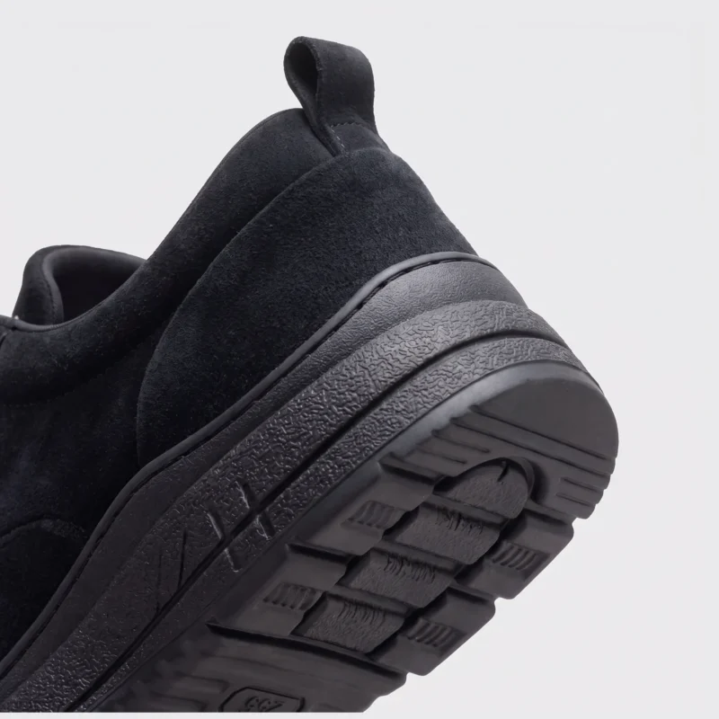 Close-up of the heel and grippy tread outsole edge of a black AZEKA fleece-lined slip-on winter shoe with pull tab