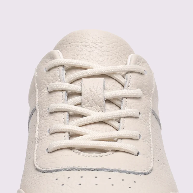 genuine leather casual sneakers breathable chunky sole in white, close-up view of the closure on a light gray background