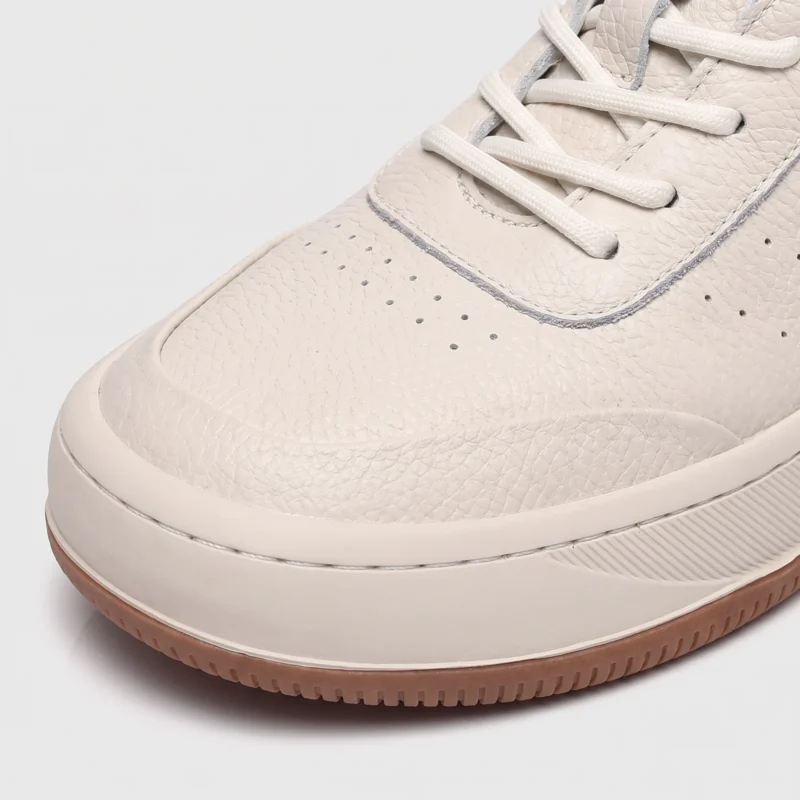 genuine leather casual sneakers breathable chunky sole in white, close-up view of the toe on a light gray background