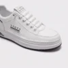 men's perforated slip-on sneakers - breathable knit casual walking shoes with cushioned sole in white, close-up view of the toe on a light gray background