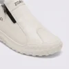 zip slip-on casual sneakers - lace-free smooth-upper shoes with a lugged thick sole in cream, close-up view of the toe on a light gray background