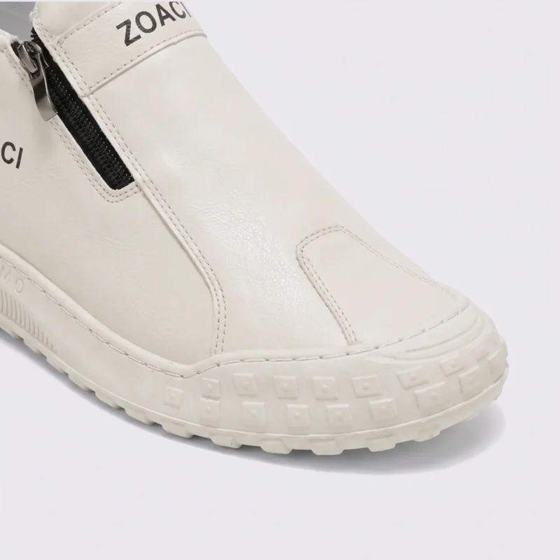 zip slip-on casual sneakers - lace-free smooth-upper shoes with a lugged thick sole in cream, close-up view of the toe on a light gray background
