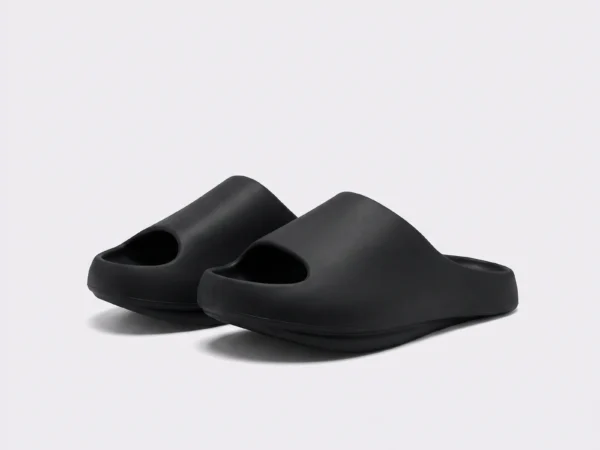 negative heel arch support slide sandals - thick platform one-piece eva slides for women in black, front 45-degree view of the pair on a light gray background