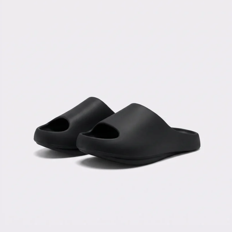 negative heel arch support slide sandals - thick platform one-piece eva slides for women in black, front 45-degree view of the pair on a light gray background