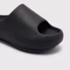 negative heel arch support slide sandals - thick platform one-piece eva slides for women in black, close-up view of the toe on a light gray background