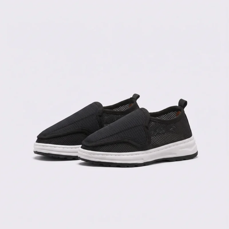wide fit soft canvas slip-on shoes breathable mesh roomy toe everyday comfort in black, front 45-degree view of the pair on a light gray background