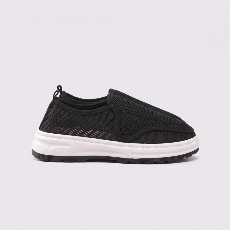wide fit soft canvas slip-on shoes breathable mesh roomy toe everyday comfort in black, left side profile view on a light gray background