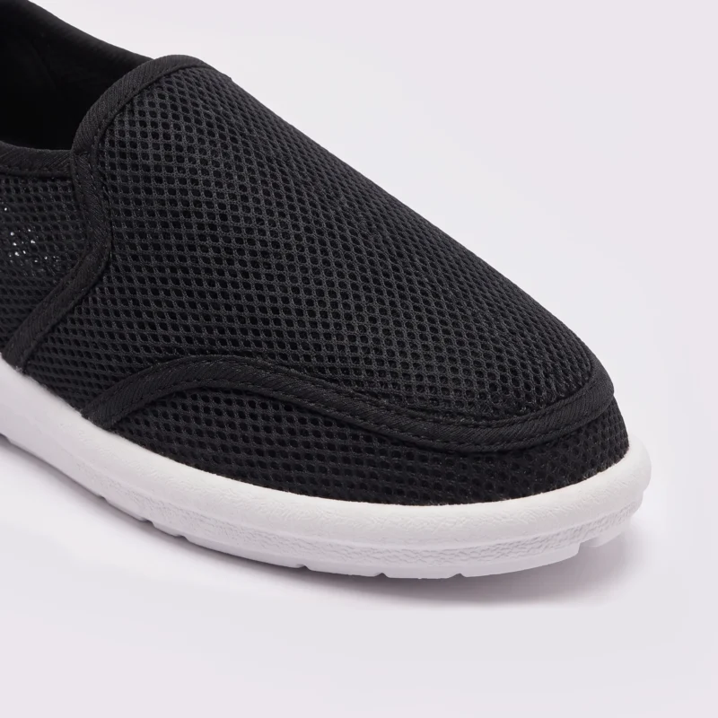 wide fit soft canvas slip-on shoes breathable mesh roomy toe everyday comfort in black, close-up view of the toe on a light gray background