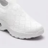slip-on quilted sock sneakers - lace-free everyday shoes with a cushioned thick sole and heel window in white, close-up view of the toe on a light gray background