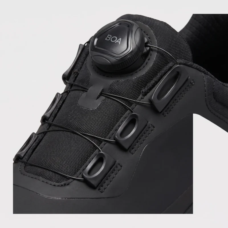 boa closure hiking sneakers in black, close-up view of the boa dial on a light gray background