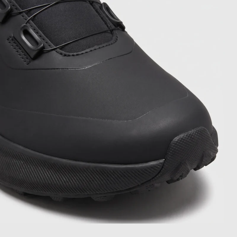 boa closure hiking sneakers in black, close-up view of the toe on a light gray background