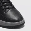 chunky sole leather casual sneakers in black, close-up view of the toe on a light gray background