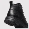 chunky sole leather ankle boots in black, close-up view of the heel on a light gray background