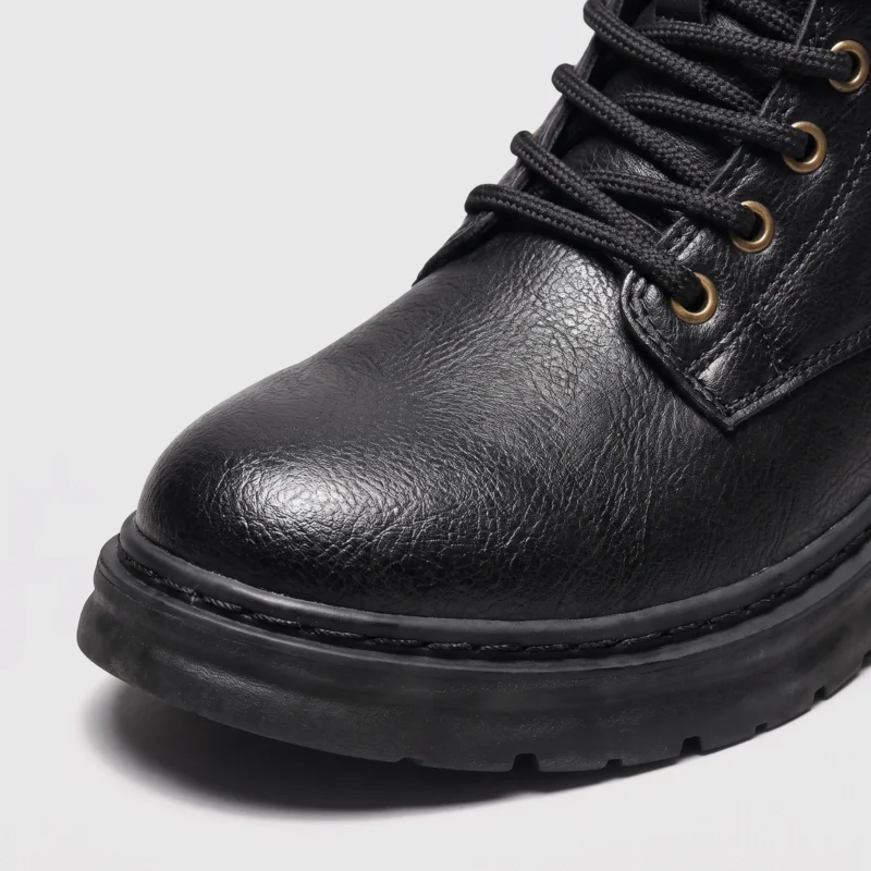 chunky sole leather ankle boots in black, close-up view of the toe on a light gray background