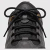 leather outdoor hiking sneakers in black, close-up view of the closure on a light gray background