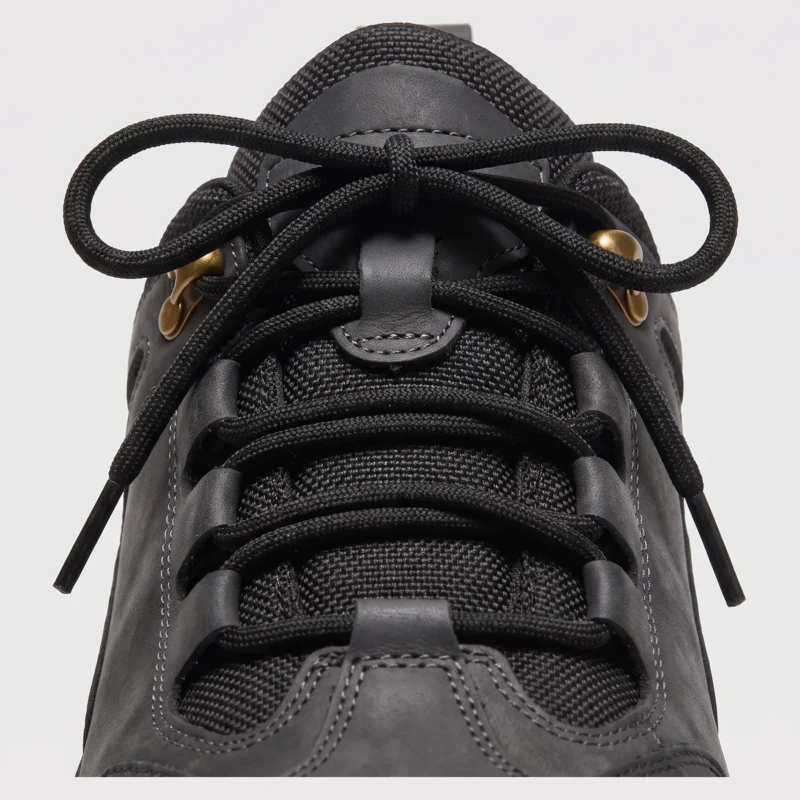 leather outdoor hiking sneakers in black, close-up view of the closure on a light gray background