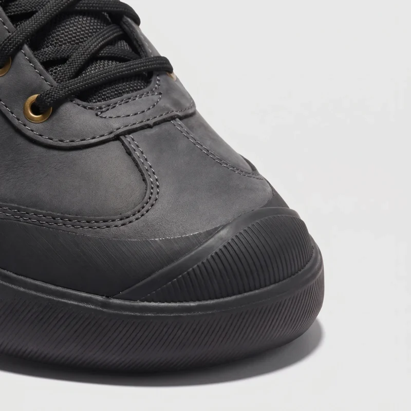 leather outdoor hiking sneakers in black, close-up view of the toe on a light gray background