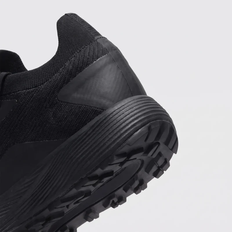 lightweight trail running sneakers in black, close-up view of the heel on a light gray background