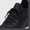 lightweight trail running sneakers in black, close-up view of the lace on a light gray background