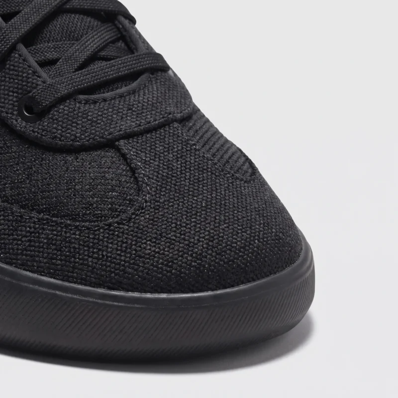 lightweight trail running sneakers in black, close-up view of the toe on a light gray background