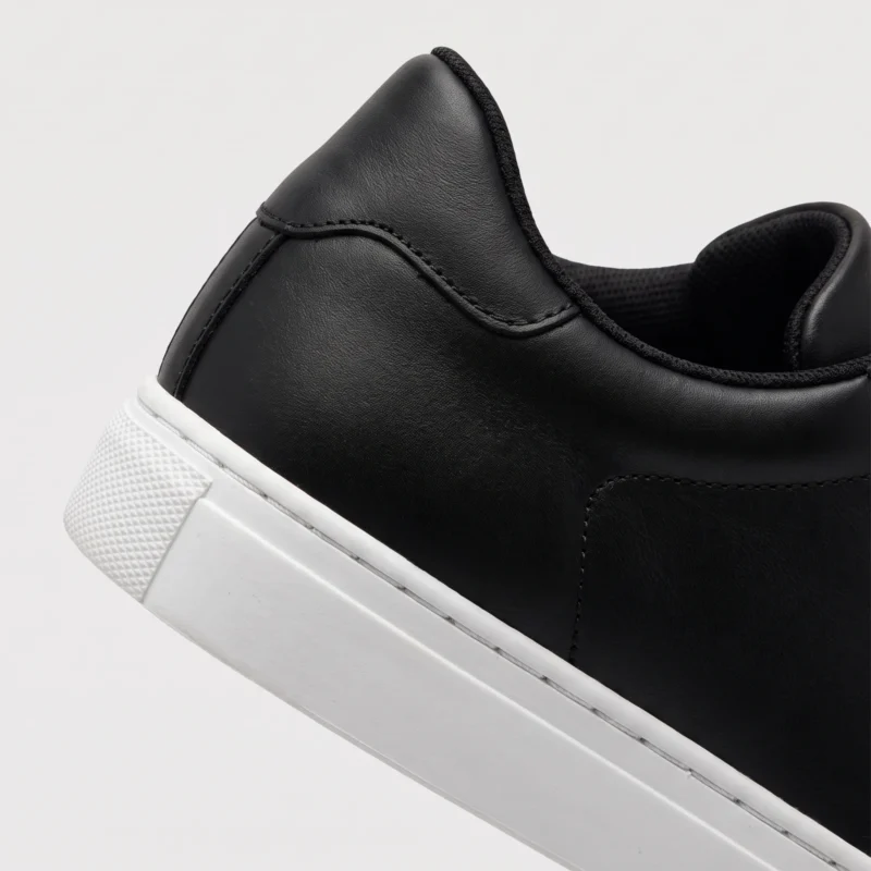 retro german trainer sneakers in black, close-up view of the heel on a light gray background