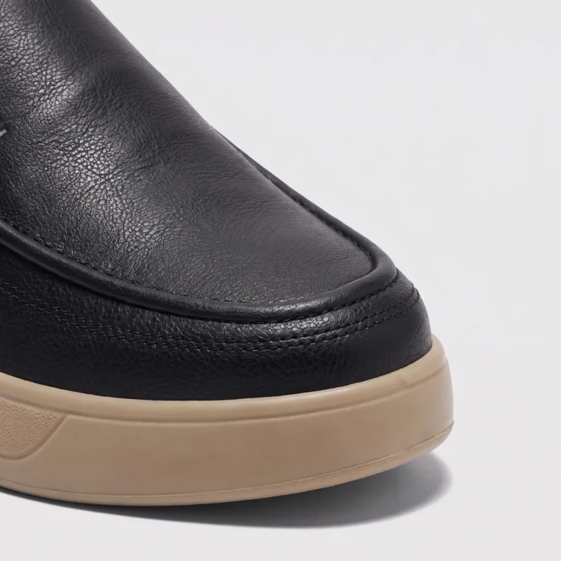 slip-on leather casual shoes in black, close-up view of the toe on a light gray background