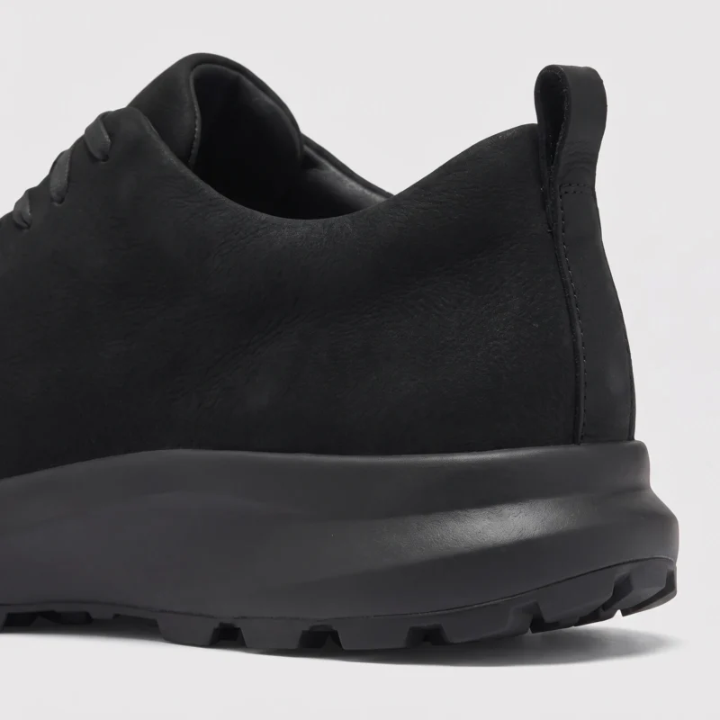 waterproof leather hiking sneakers in black, close-up view of the matte heel on a light gray background