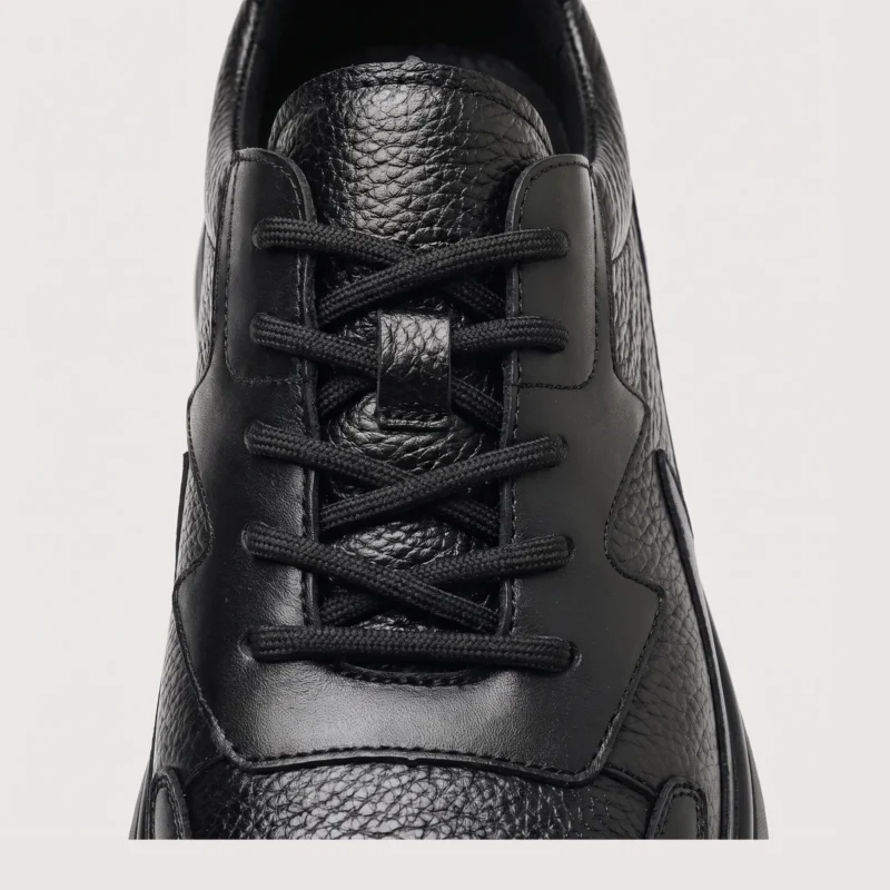 genuine leather casual shoes breathable lightweight non-slip walking sneakers in black, close-up view of the closure on a light gray background