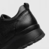 genuine leather casual shoes breathable lightweight non-slip walking sneakers in black, close-up view of the heel on a light gray background