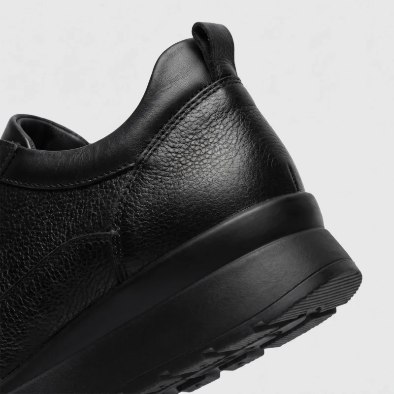 genuine leather casual shoes breathable lightweight non-slip walking sneakers in black, close-up view of the heel on a light gray background