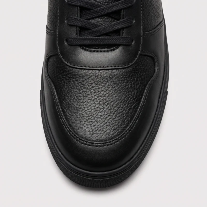 genuine leather casual shoes breathable lightweight non-slip walking sneakers in black, close-up view of the toe on a light gray background