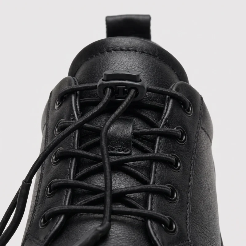 genuine leather lace-up casual sneakers warm comfortable in black, close-up view of the closure on a light gray background