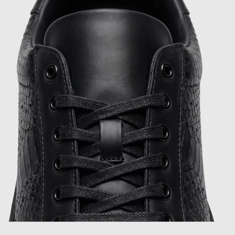 genuine leather business casual sneakers lightweight comfortable non-slip walking shoes in black, close-up view of the closure on a light gray background
