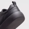 genuine leather business casual running sneakers in black, close-up view of the heel on a light gray background