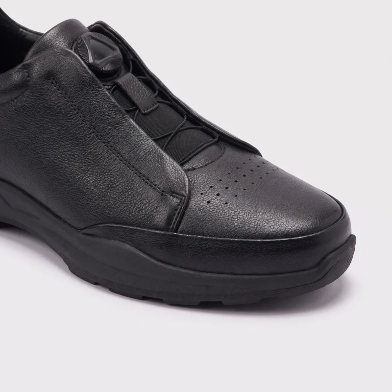 genuine leather business casual running sneakers in black, close-up view of the toe on a light gray background