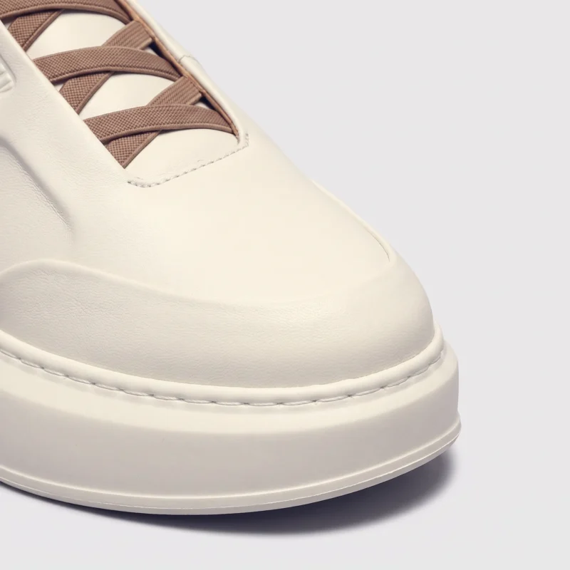 genuine leather platform sneakers, close-up view of the toe on a light gray background