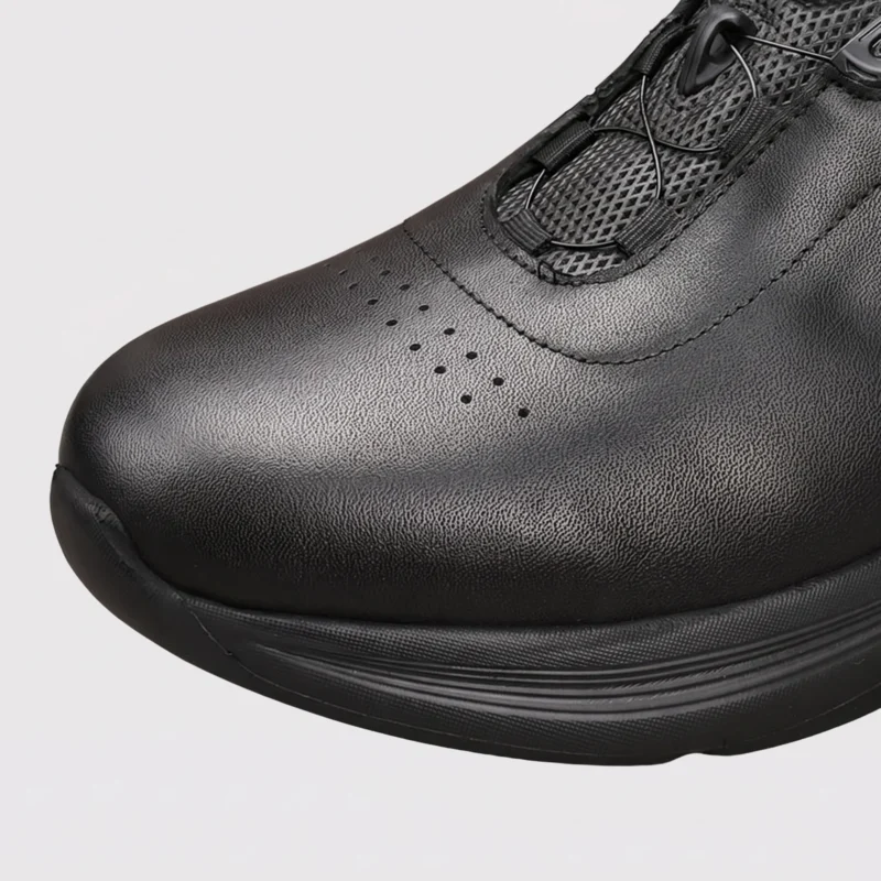 genuine leather rotating dial casual sneakers breathable lightweight in black, close-up view of the toe on a light gray background