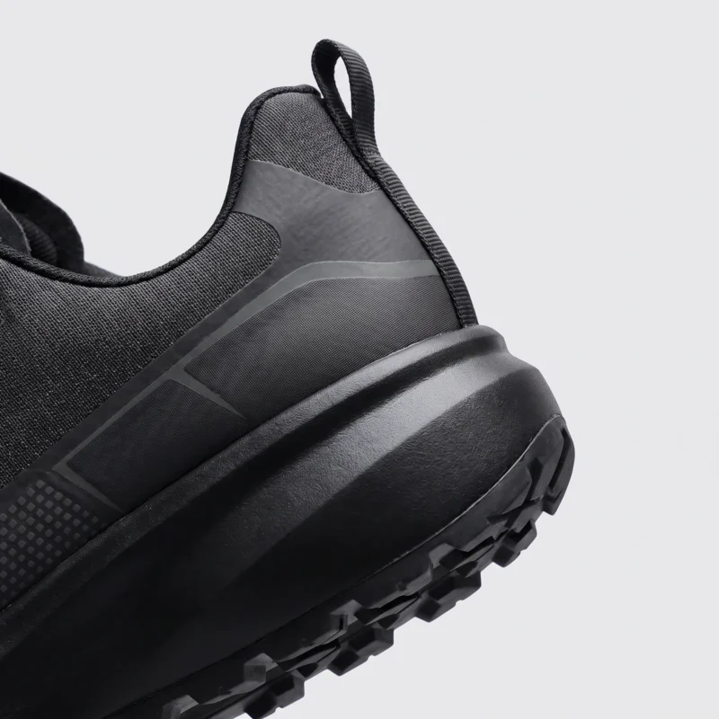 trendy rotating dial closure casual sneakers breathable chunky sole commuter shoes in black, close-up view of the heel on a light gray background