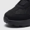 trendy rotating dial closure casual sneakers breathable chunky sole commuter shoes in black, close-up view of the toe on a light gray background
