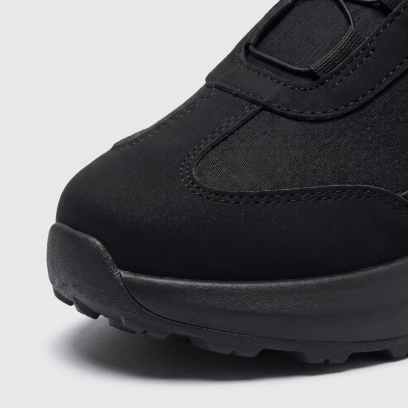 trendy rotating dial closure casual sneakers breathable chunky sole commuter shoes in black, close-up view of the toe on a light gray background